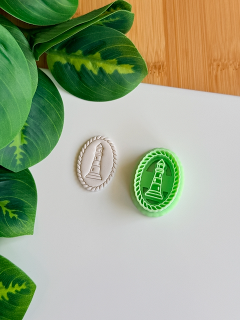 Lighthouse clay cutter and its white clay impression on a white surface next to green leaves. 