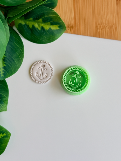 A top-down view of a mint green 3D-printed circular clay cutter featuring an anchor emblem and a rope-textured border, paired with a white polymer clay disc showing the crisp, embossed impression of the same nautical design on a clean white surface.